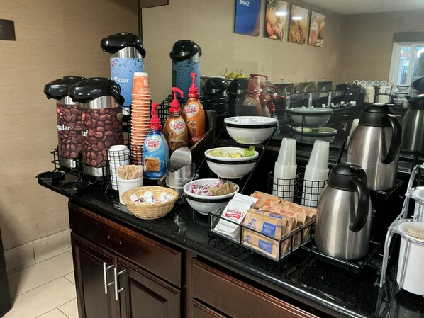 A buffet setup with coffee dispensers, coffee mugs, and food containers. - Continental Inn San Diego Hotel Escondido (Escondido)
