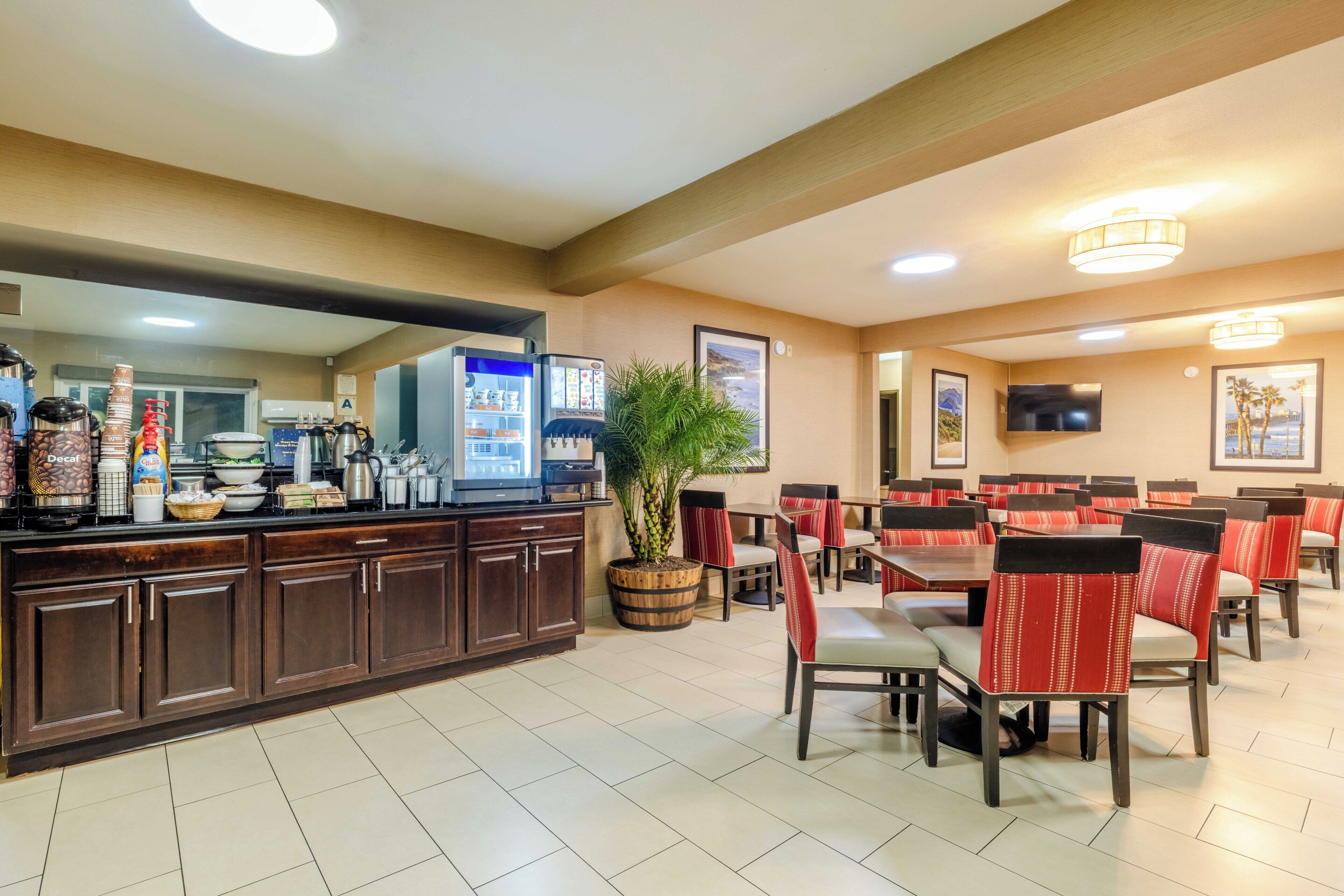 A restaurant with a counter, dining area, and a TV mounted on the wall.