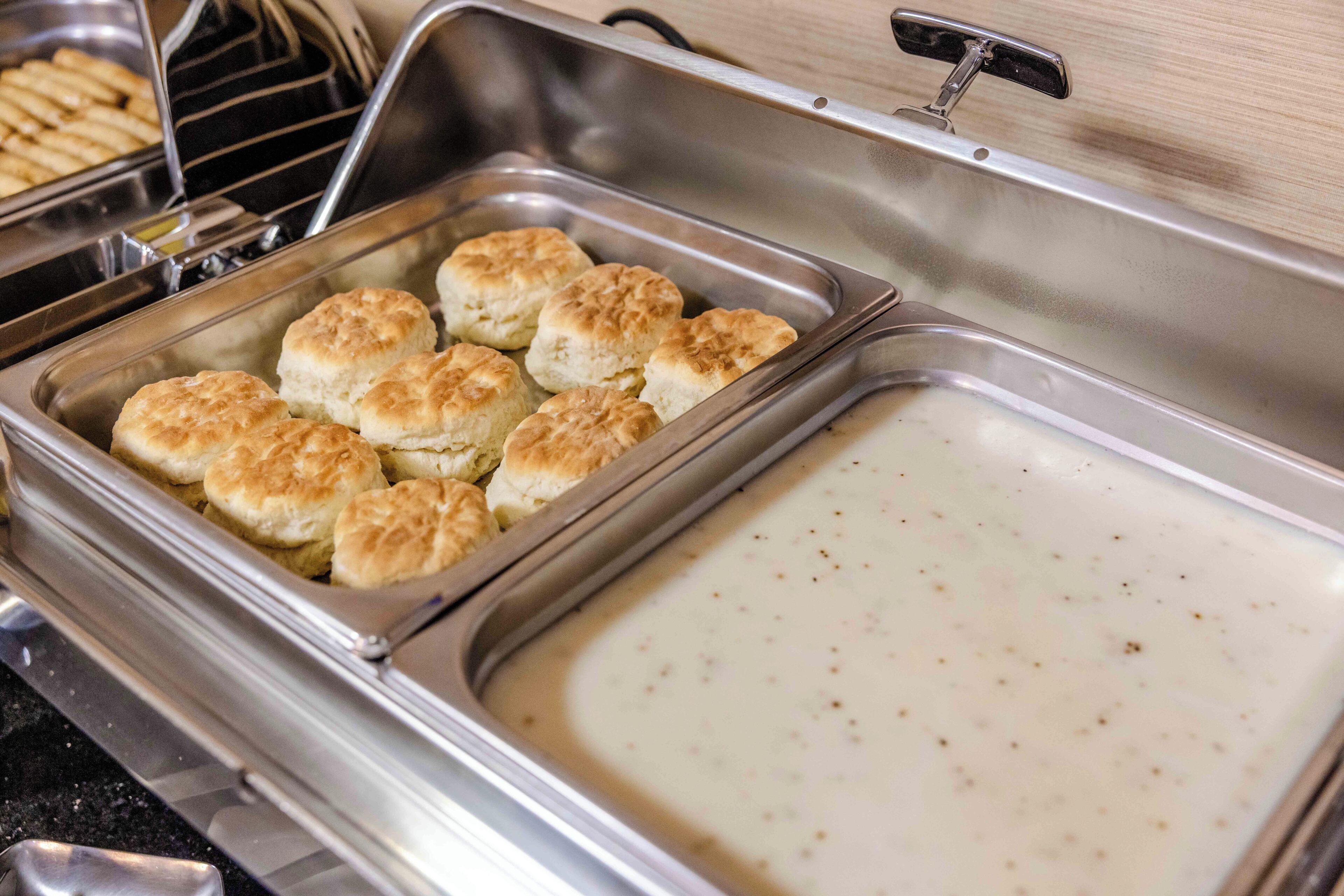 Un buffet avec un récipient rempli de biscuits et un grand plat de service contenant de la sauce.