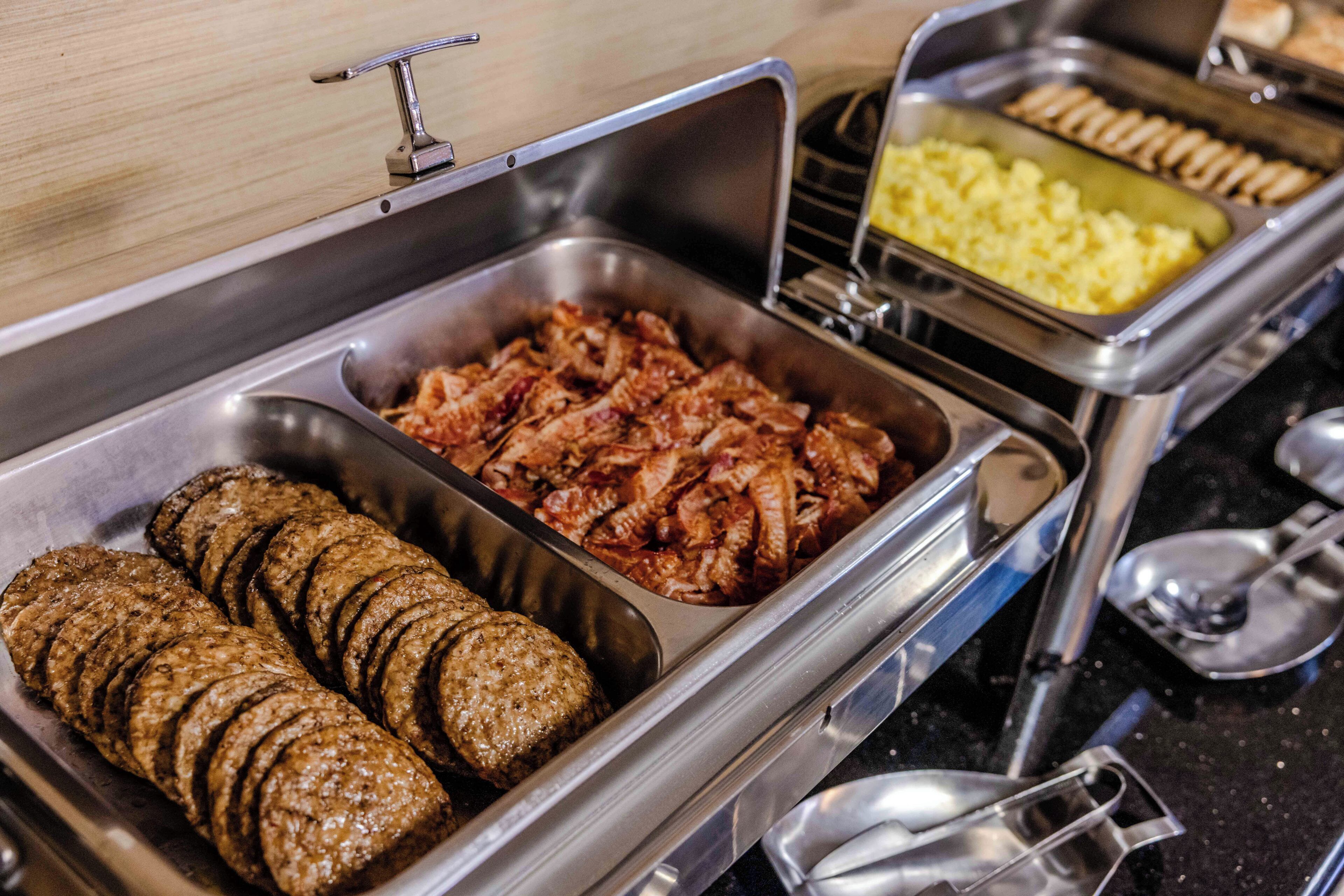 Un bufé con distintos alimentos, incluyendo carnes en rodajas y un recipiente con guiso.
