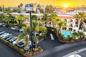 Un hotel con un letrero que dice 'Continental Inn', un estacionamiento, una piscina y una montaña al fondo.