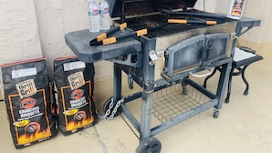 A charcoal grill with two bags of charcoal, two bottles of water, and a bottle of barbecue sauce. - Continental Inn San Diego Hotel Escondido (Escondido)