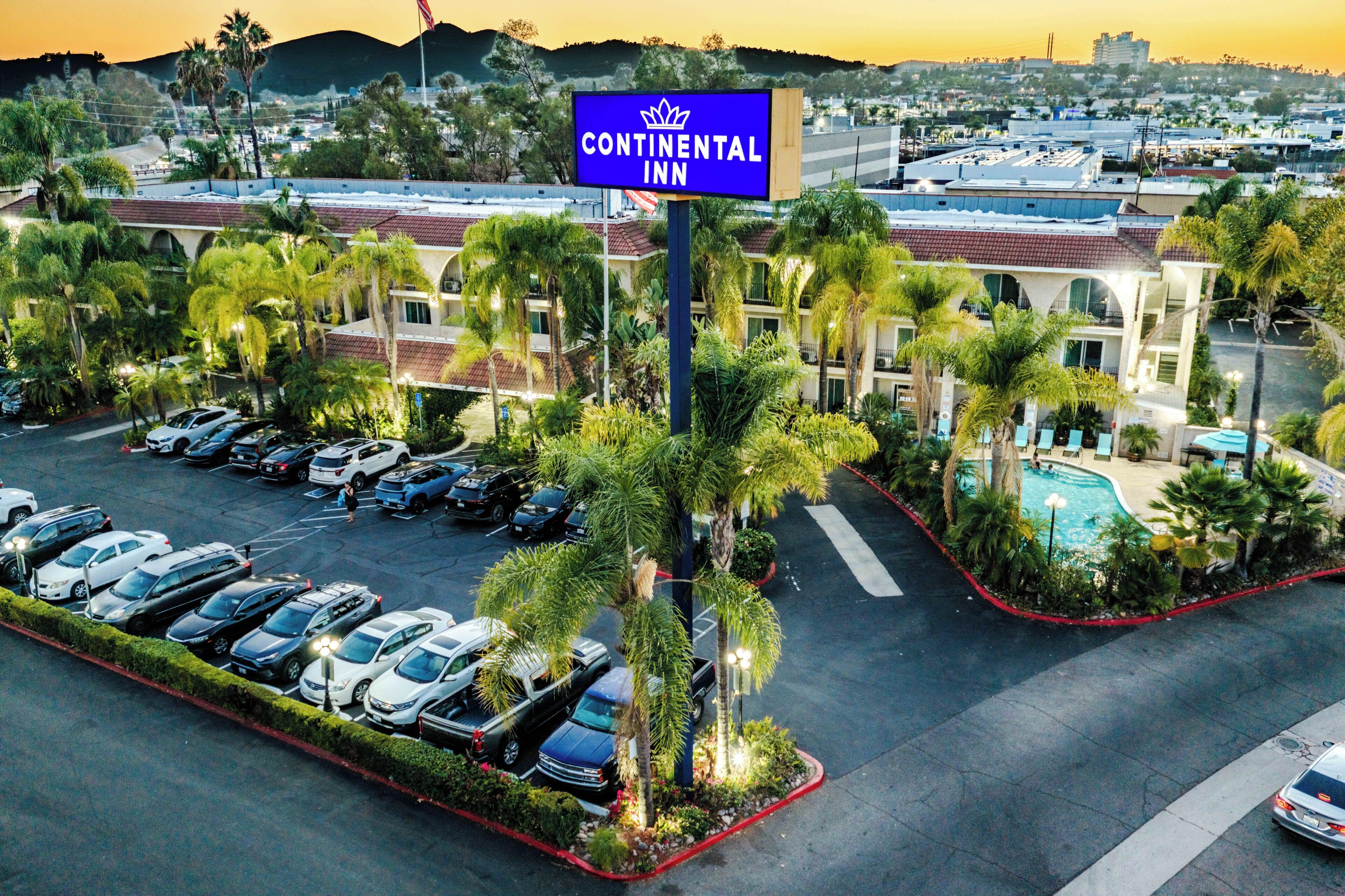 A hotel with a pool, multiple parking spaces, and a sign indicating it's a Continental Inn.