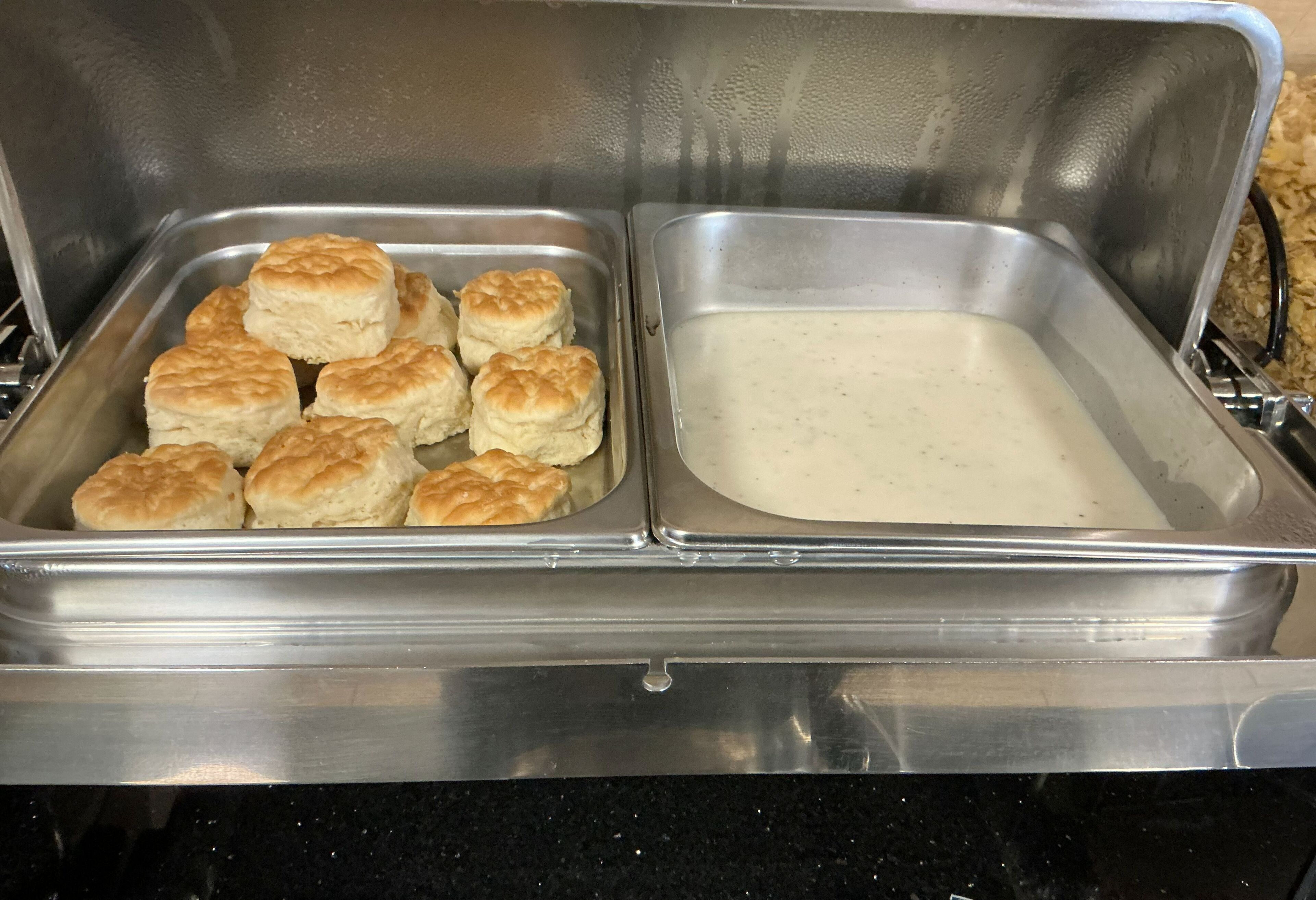 A stainless steel buffet with two compartments, one containing biscuits and the other with a creamy substance.