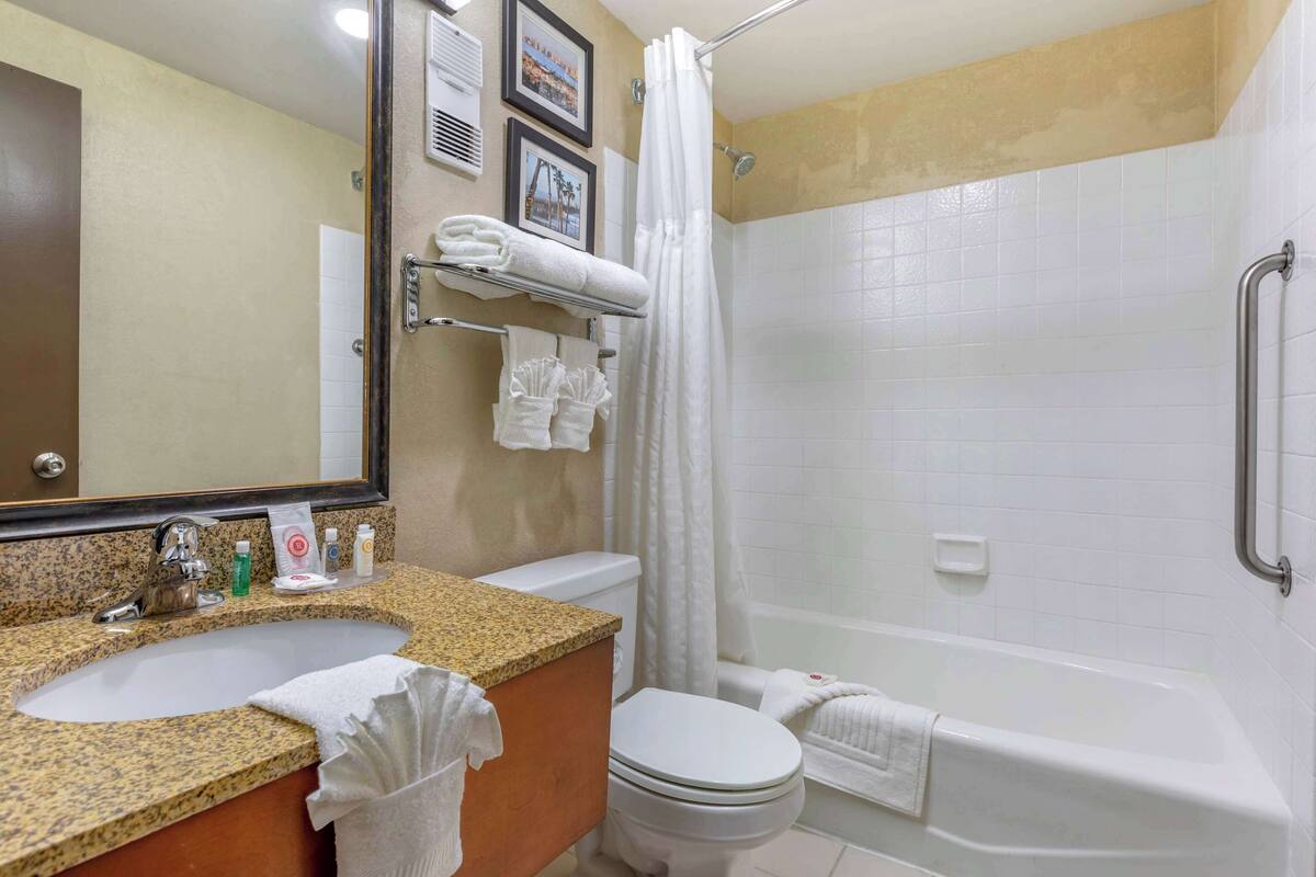 Un bagno con lavabo in granito, toilette, vasca e tenda doccia.