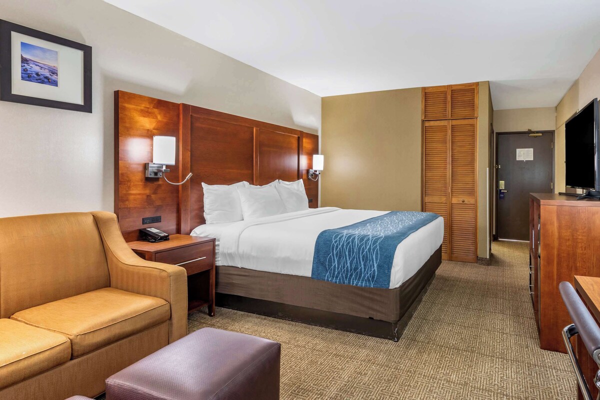 Ein Hotelzimmer mit Bett, Schreibtisch, Stuhl, Fernseher und Kleiderschrank.