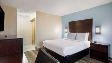 Una habitación de hotel con cama, mesita de noche y escritorio con silla.