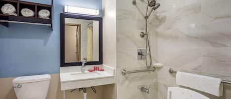 A bathroom with a toilet, sink, mirror, shower, and a towel rack.