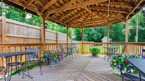 Eine überdachte Terrasse mit Holzboden, Metallstühlen und -tischen.