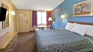 A hotel room with a bed, a desk, a chair, a TV, and a painting on the wall. - Days Inn by Wyndham Lawrenceville (Lawrenceville)