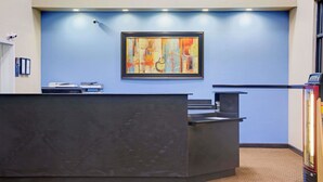 A reception desk with a framed abstract painting above it, a security camera on the wall, and a vending machine to the right. - Days Inn by Wyndham Lawrenceville (Lawrenceville)