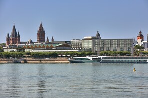 A river with a boat, a bridge, and buildings including a hotel with a dome and a modern glass building.