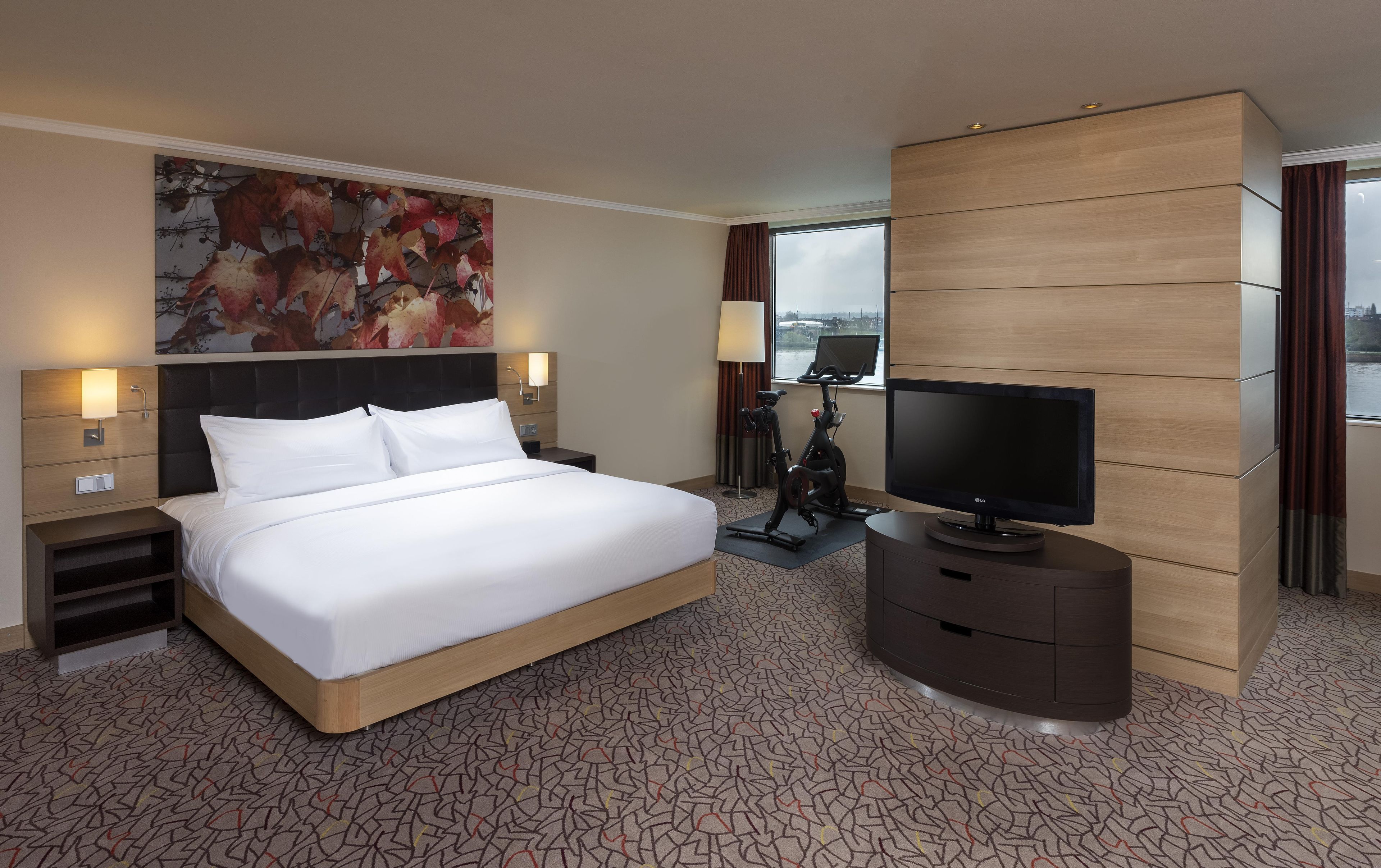 Une chambre d’hôtel avec un grand lit, une télévision, un bureau et une vue sur la ville.