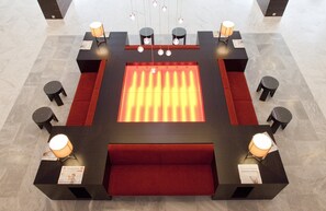 A lobby with a central heated floor, seating areas, and tables with lamps. - Hilton Mainz (Mainz)