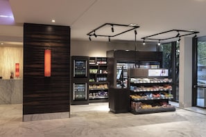 A modern retail space with a marble floor, a reception area with a vertical light feature, and shelves stocked with various products. - Hilton Mainz (Mainz)