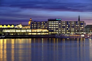 A hotel with a modern design, a prominent Hilton sign, and a view of the water.