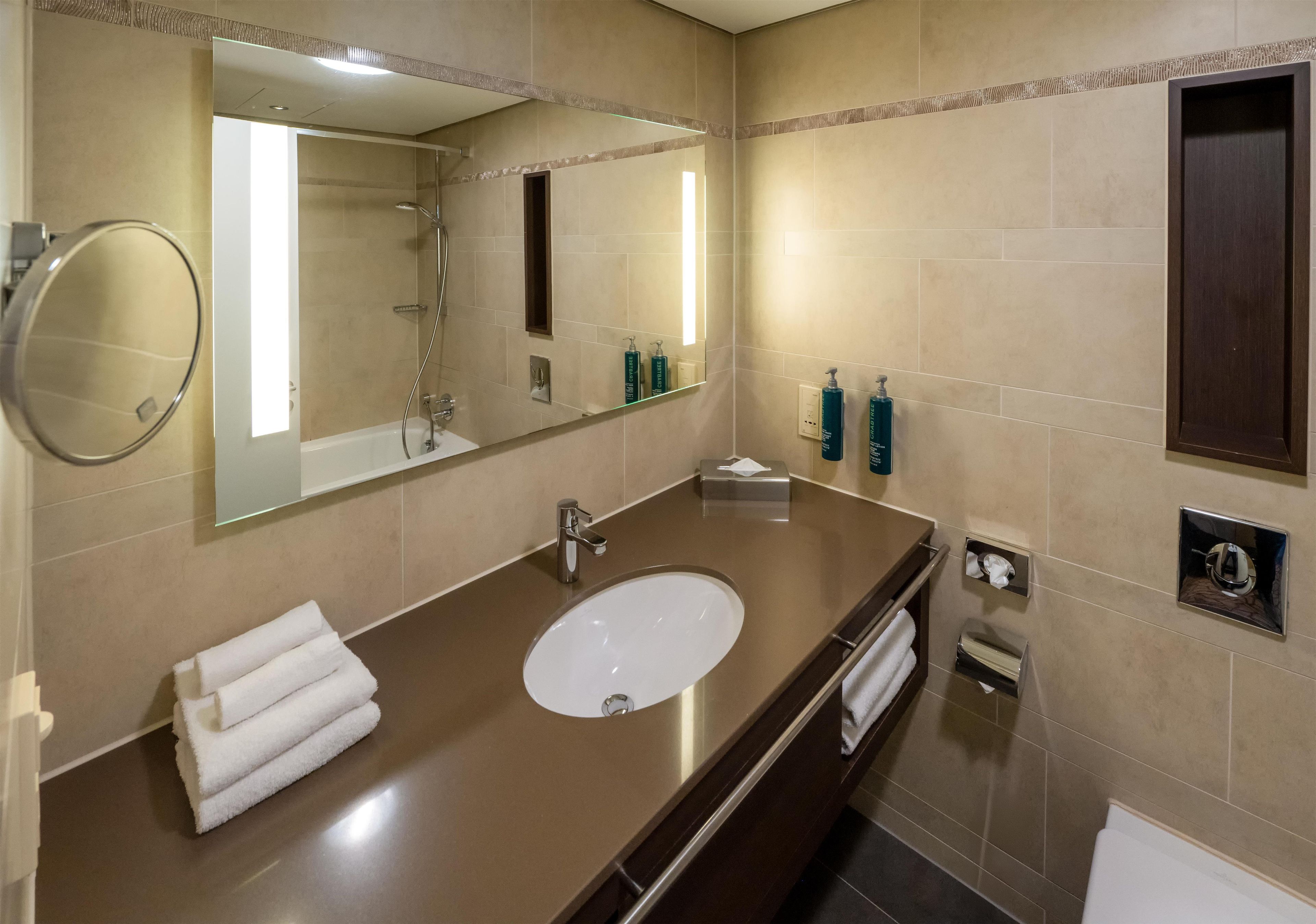 Une salle de bain moderne avec un grand miroir, un lavabo et une douche.