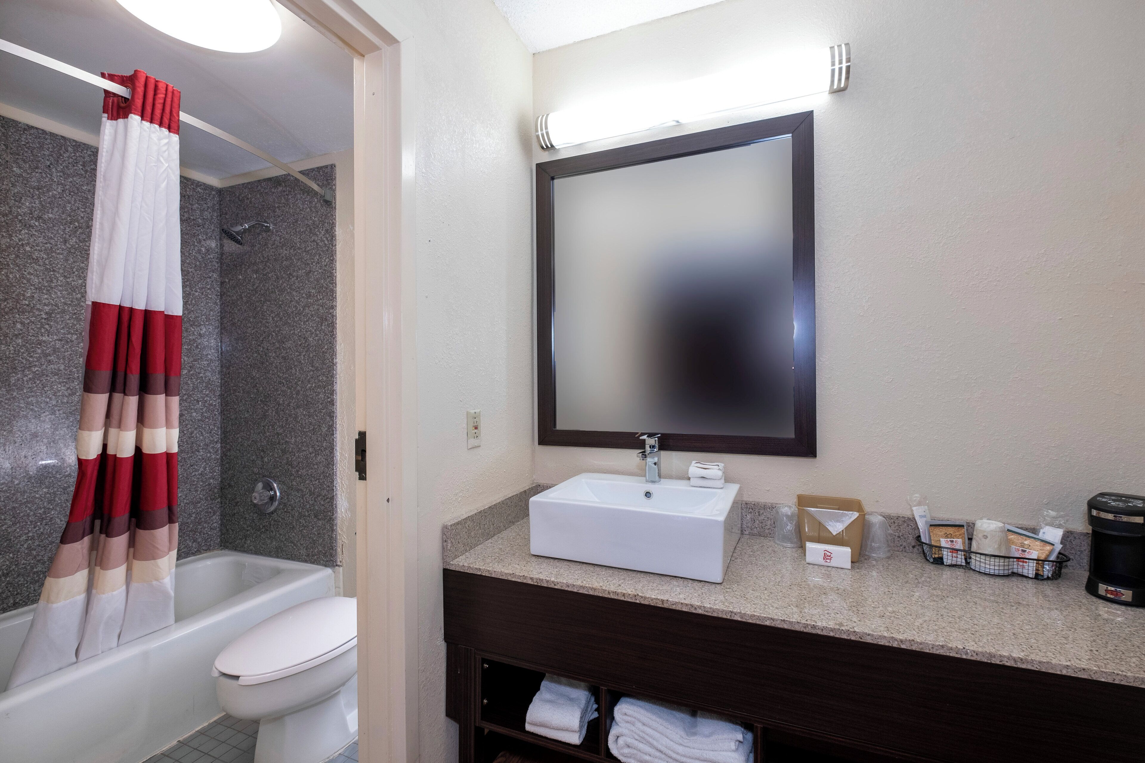A bathroom with a shower, toilet, sink, and a mirror.