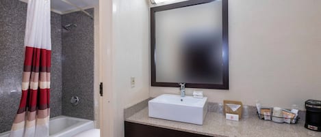 A bathroom with a shower, toilet, sink, and a mirror.