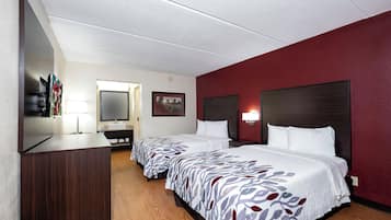 A hotel room with two beds, a TV, a desk, and a mirror.