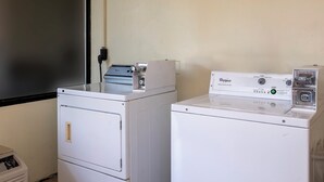 A laundry room with two stacked washers and a dryer, a utility room with a door, and a wall-mounted electrical outlet. - Red Roof Inn Kenly – I-95 (Kenly)