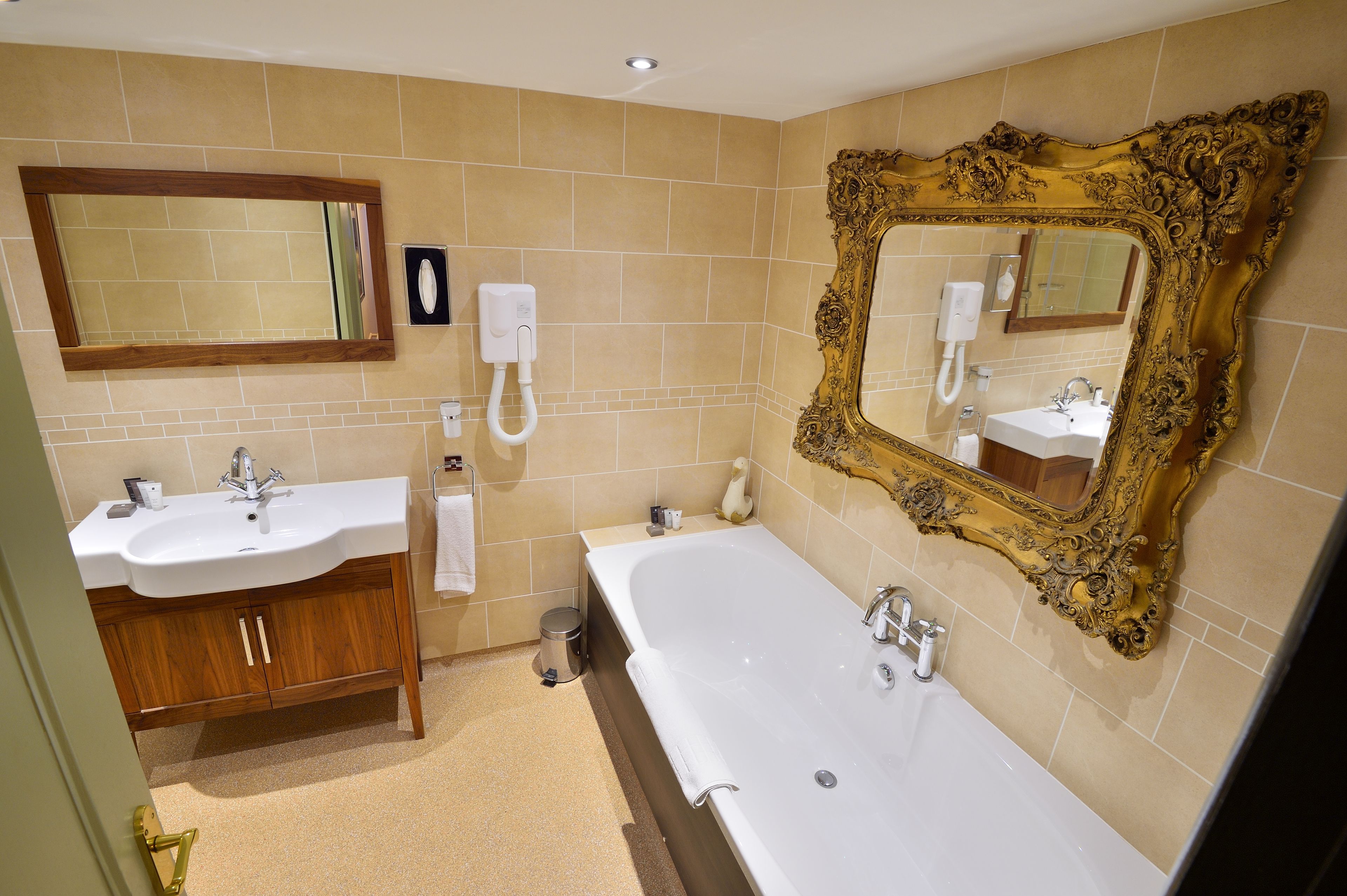 A bathroom with two sinks, a bathtub, and a large ornate mirror.
