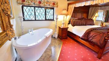 A bedroom with a large bathtub, a wooden bed with a canopy, and a window with floral curtains.