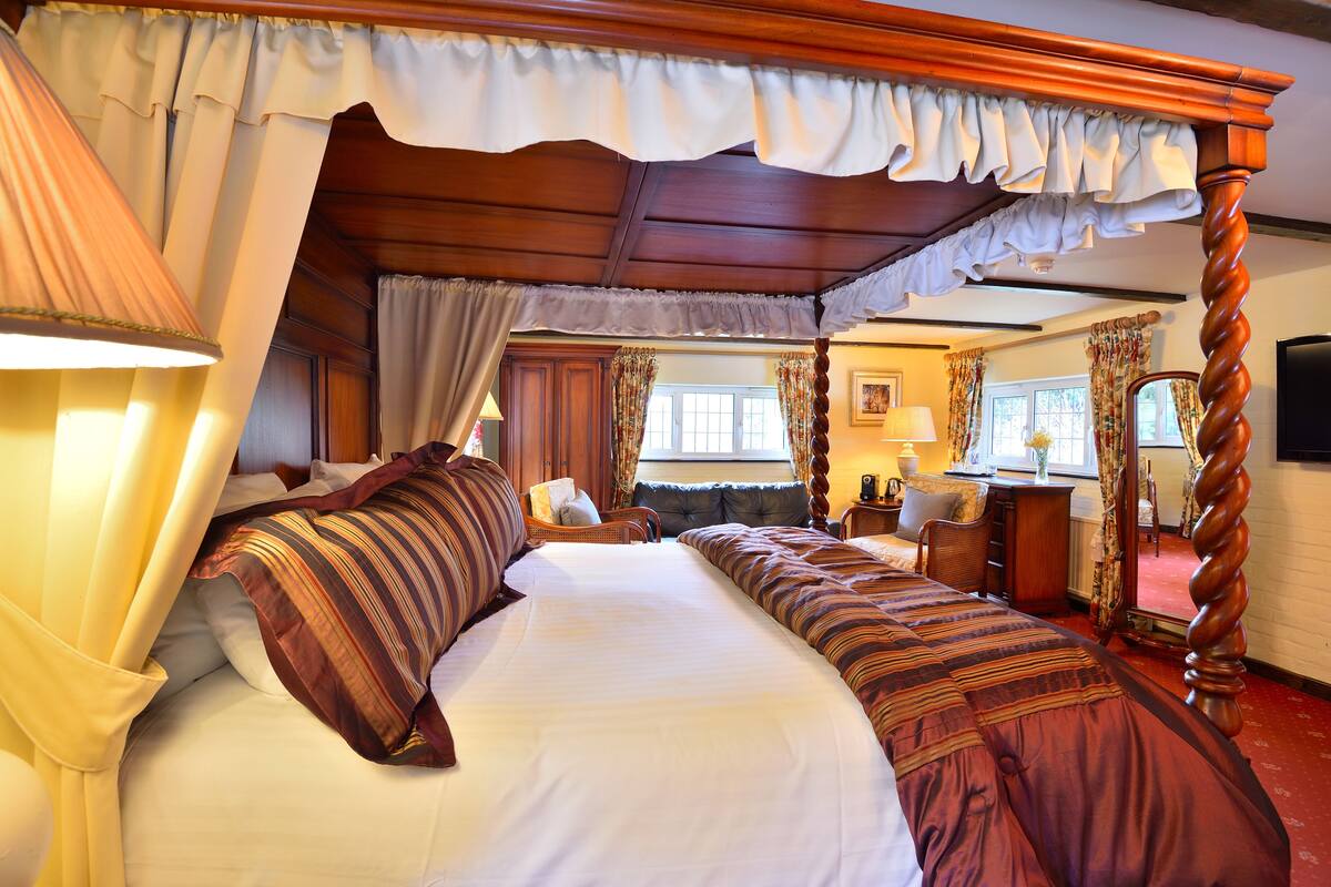 A four-poster canopy bed with a wooden frame, white bedding, and striped pillows.