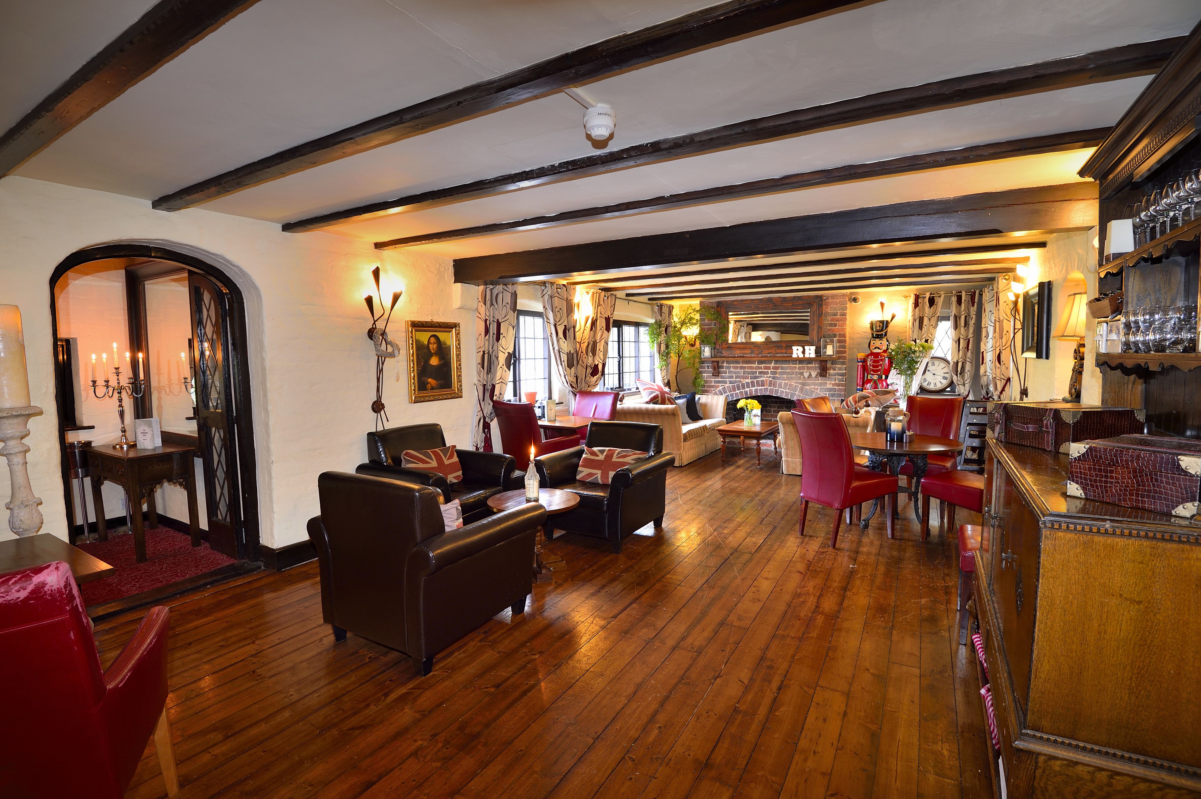 A cozy pub with wooden floors, leather sofas, and a brick fireplace.