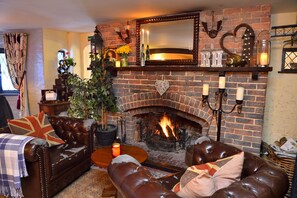 Un salón acogedor con chimenea de ladrillo, sofás de cuero y una mesa de centro.