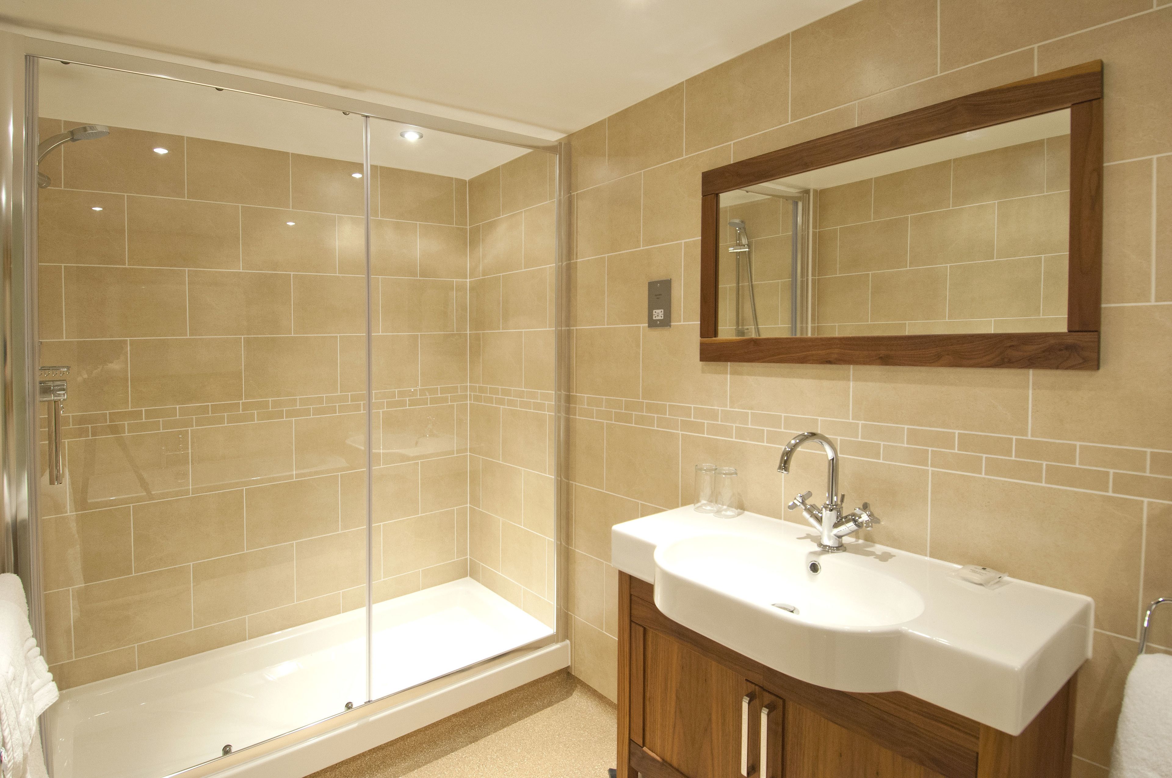 A modern bathroom with a glass-enclosed shower, a white sink, and wooden cabinets.