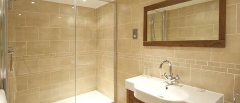 A modern bathroom with a glass-enclosed shower, a white sink, and wooden cabinets.