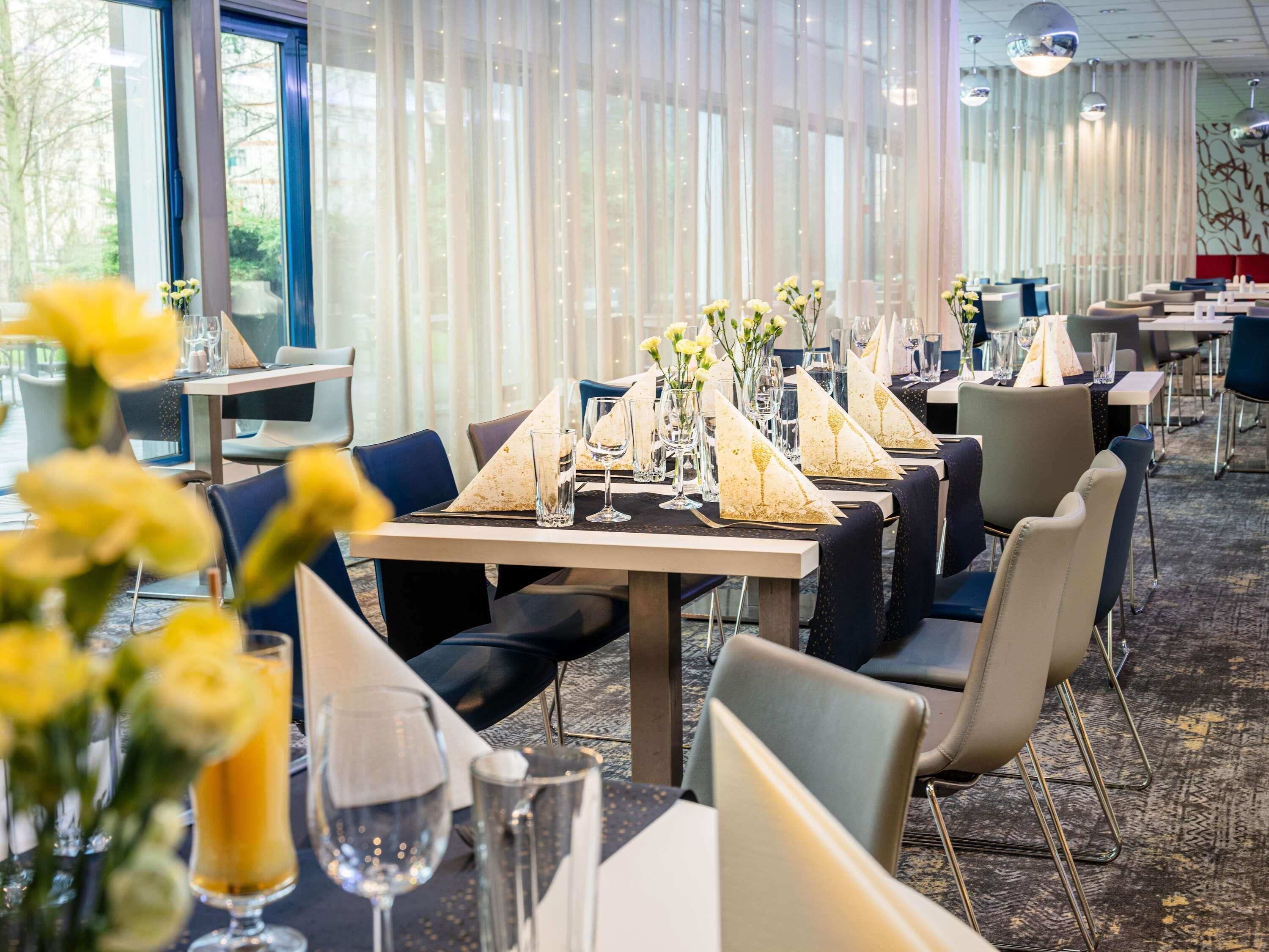Un restaurant où les tables sont dressées pour le service, avec des serviettes blanches et de la verrerie élégante.