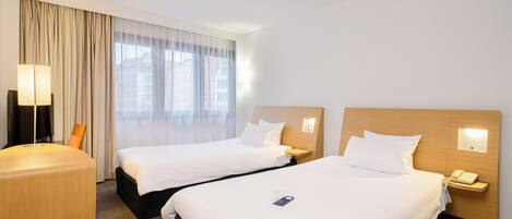 Une chambre d’hôtel avec deux lits, un bureau et une lampe.