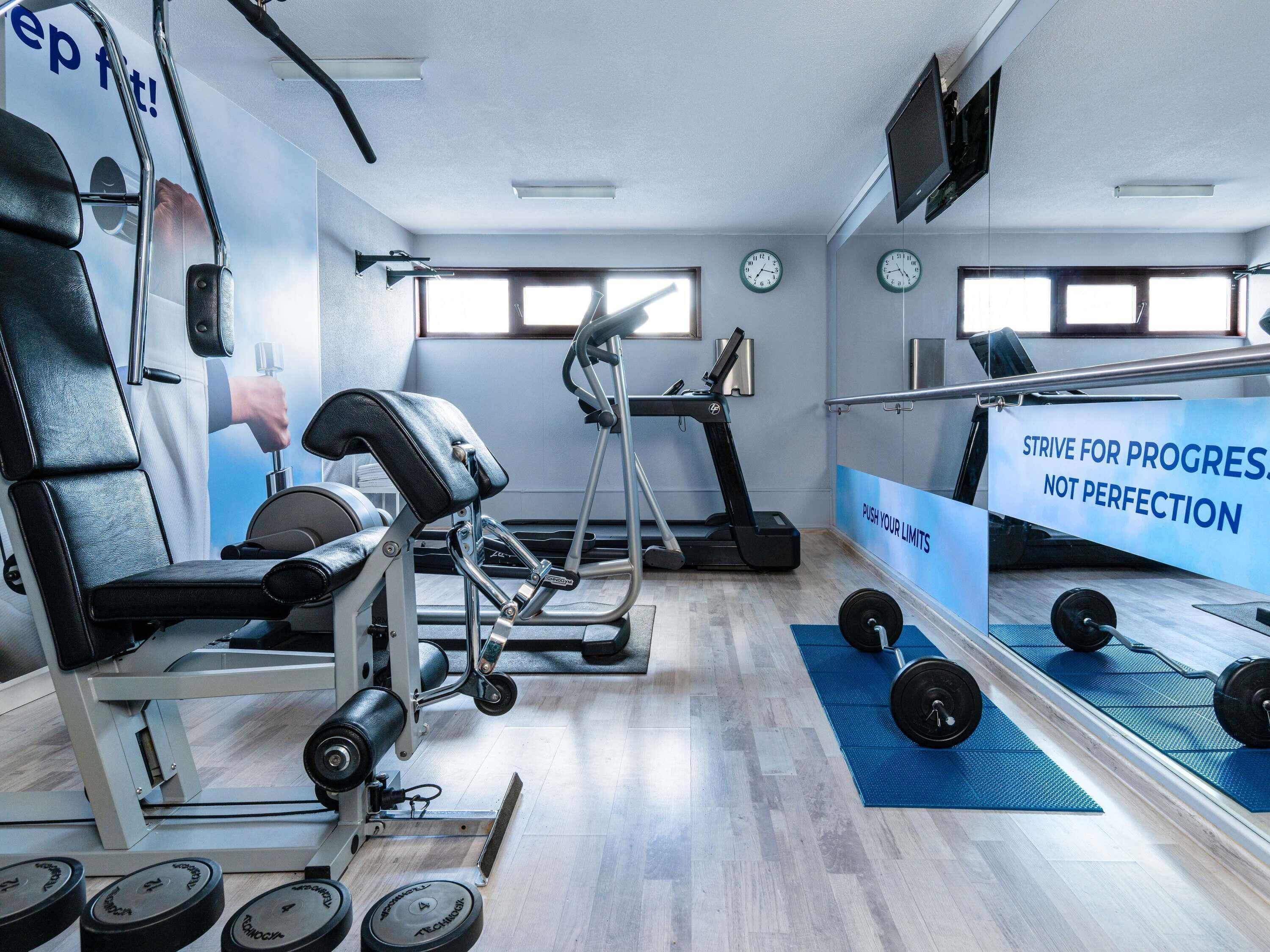 A gym with exercise equipment, motivational posters, and a mirror.