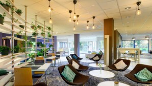 Een moderne zithoek met zitplaatsen, tafels en een plantenwand.