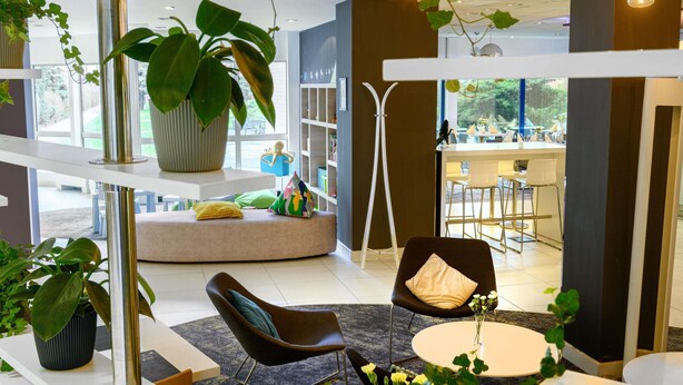 Een modern interieur met een zithoek, een grote potplant en uitzicht op de eetruimte.