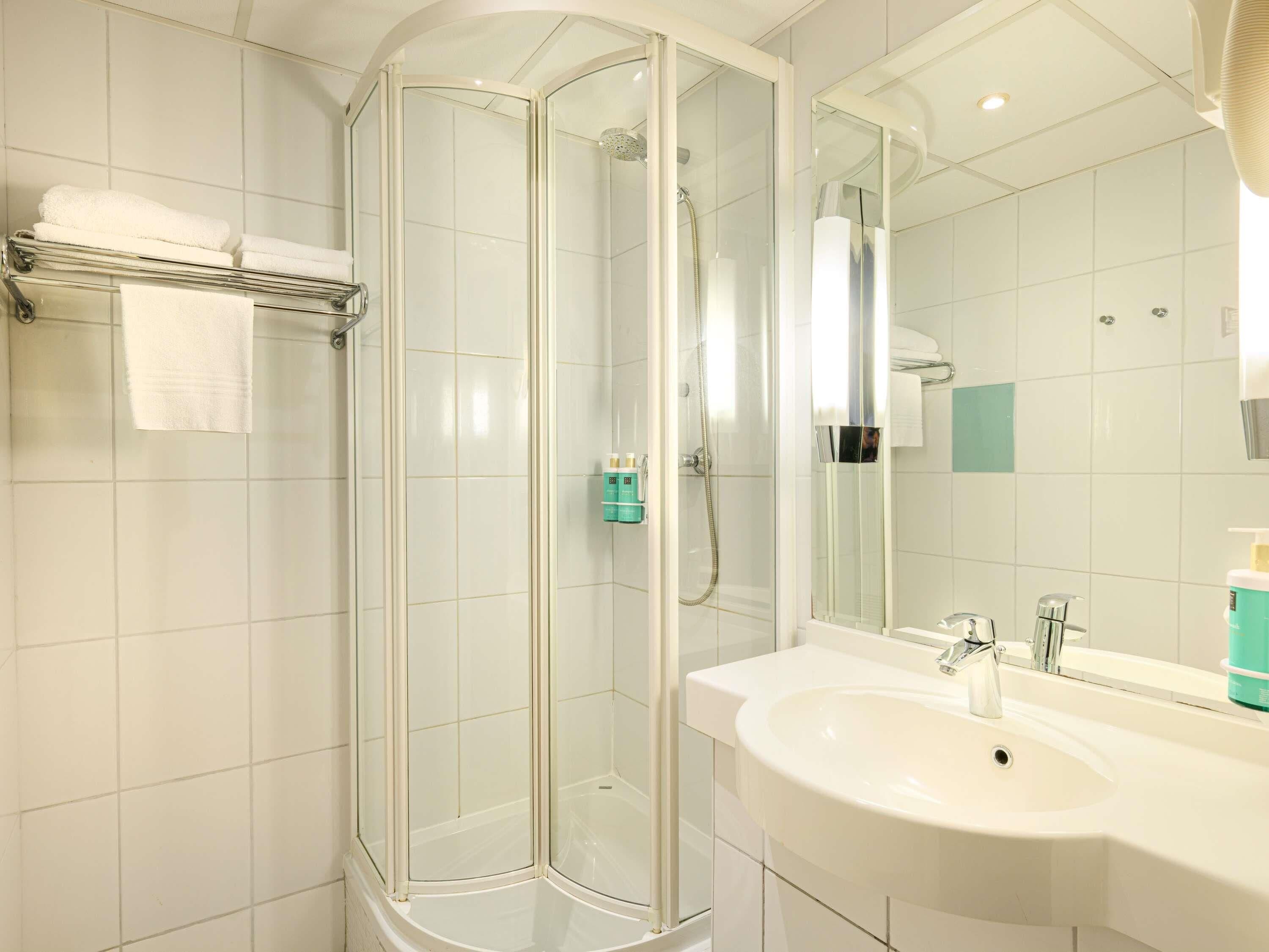A modern bathroom with a glass-enclosed shower, a white sink, and a large mirror.