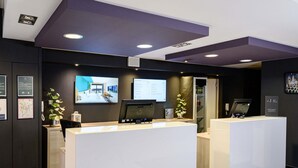 Een modern receptiegebied met twee witte receptiebalies, een scherm waarop een kaart wordt weergegeven en een wandairconditioning.