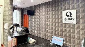 A hotel reception area with a modern design, featuring a reception desk, a mounted television, and a welcome sign. - Quality Inn & Suites Greenville I-65 (Greenville)