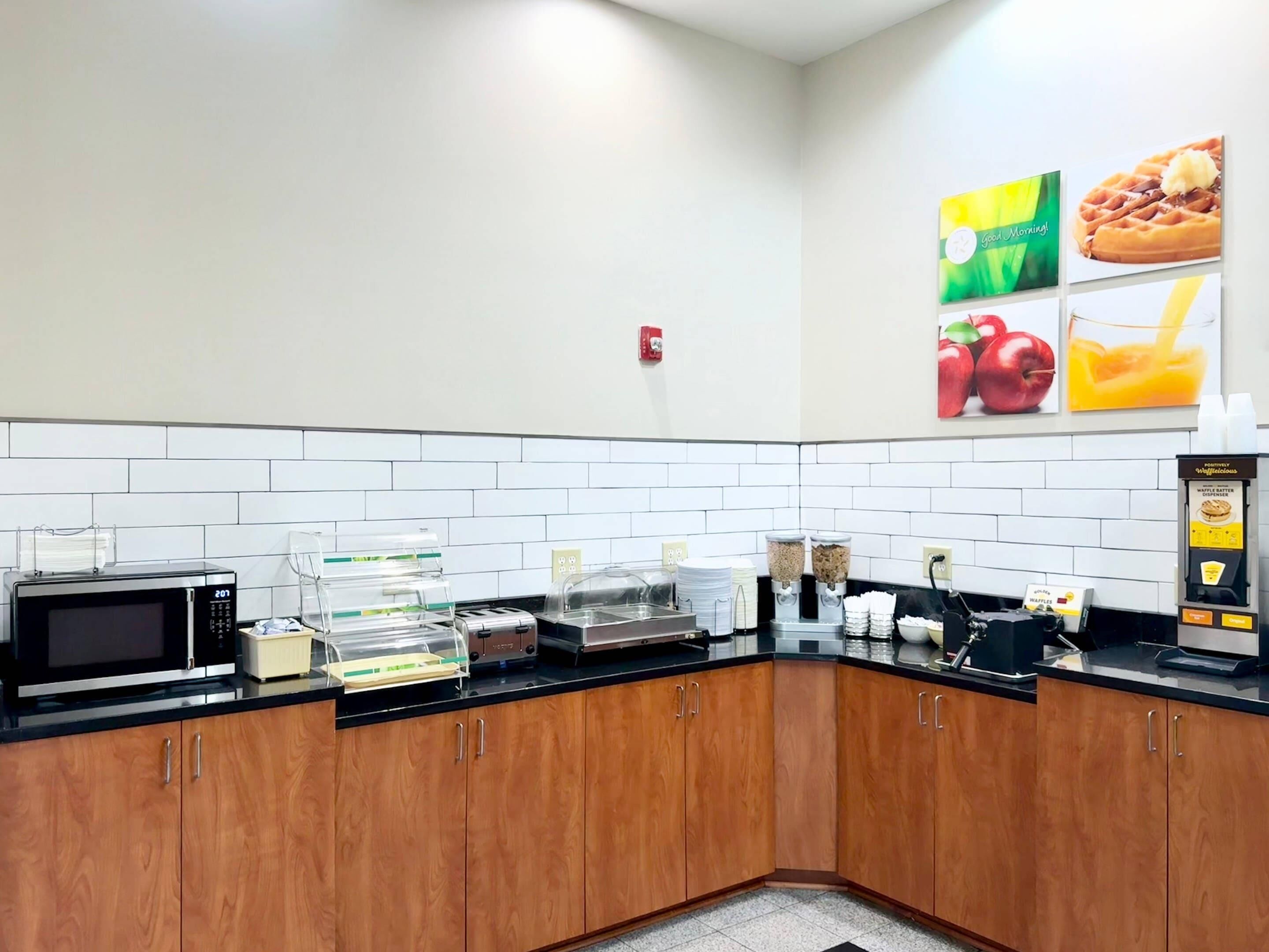 A kitchen with a microwave, toaster, waffle maker, and coffee machine.