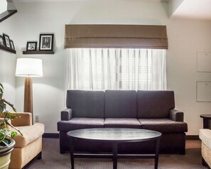 A living room with a sofa, a round coffee table, a lamp, and a potted plant. - Rodeway Inn Boise Airport (Boise)