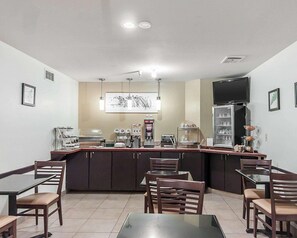 A restaurant with a counter, chairs, tables, a coffee machine, a refrigerator, and a TV mounted on the wall. - Rodeway Inn Boise Airport (Boise)