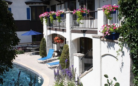 A hotel with a pool, outdoor seating, and flower boxes on balconies.