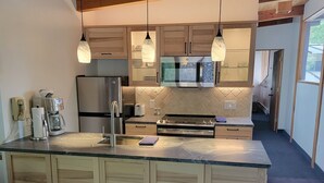 Una cocina moderna con armarios de madera, un refrigerador de acero inoxidable, horno empotrado y una isla grande con encimera de granito.
