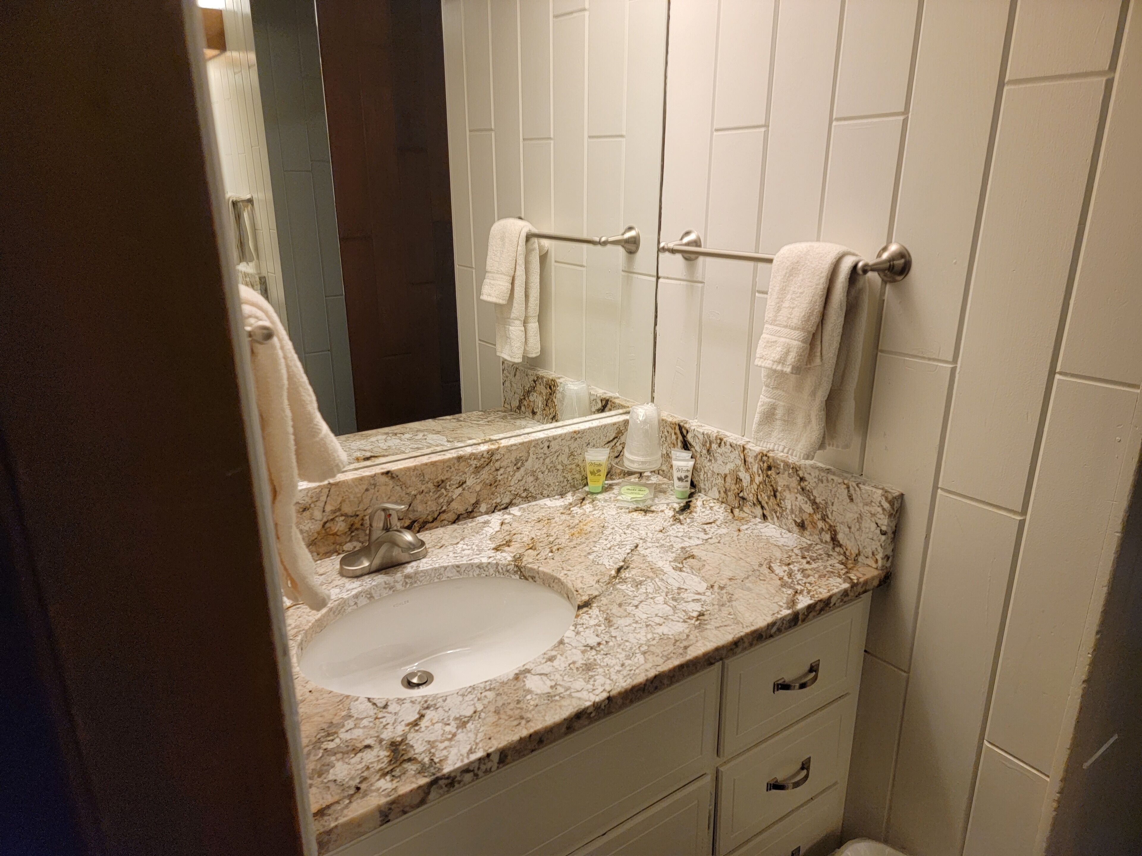 Une salle de bain avec un lavabo en marbre, un miroir et un porte-serviettes.