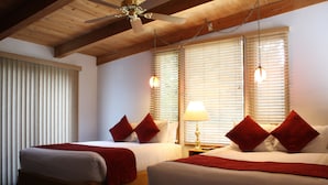 Habitación de hotel con dos camas, vigas de madera en el techo y un ventilador de techo.