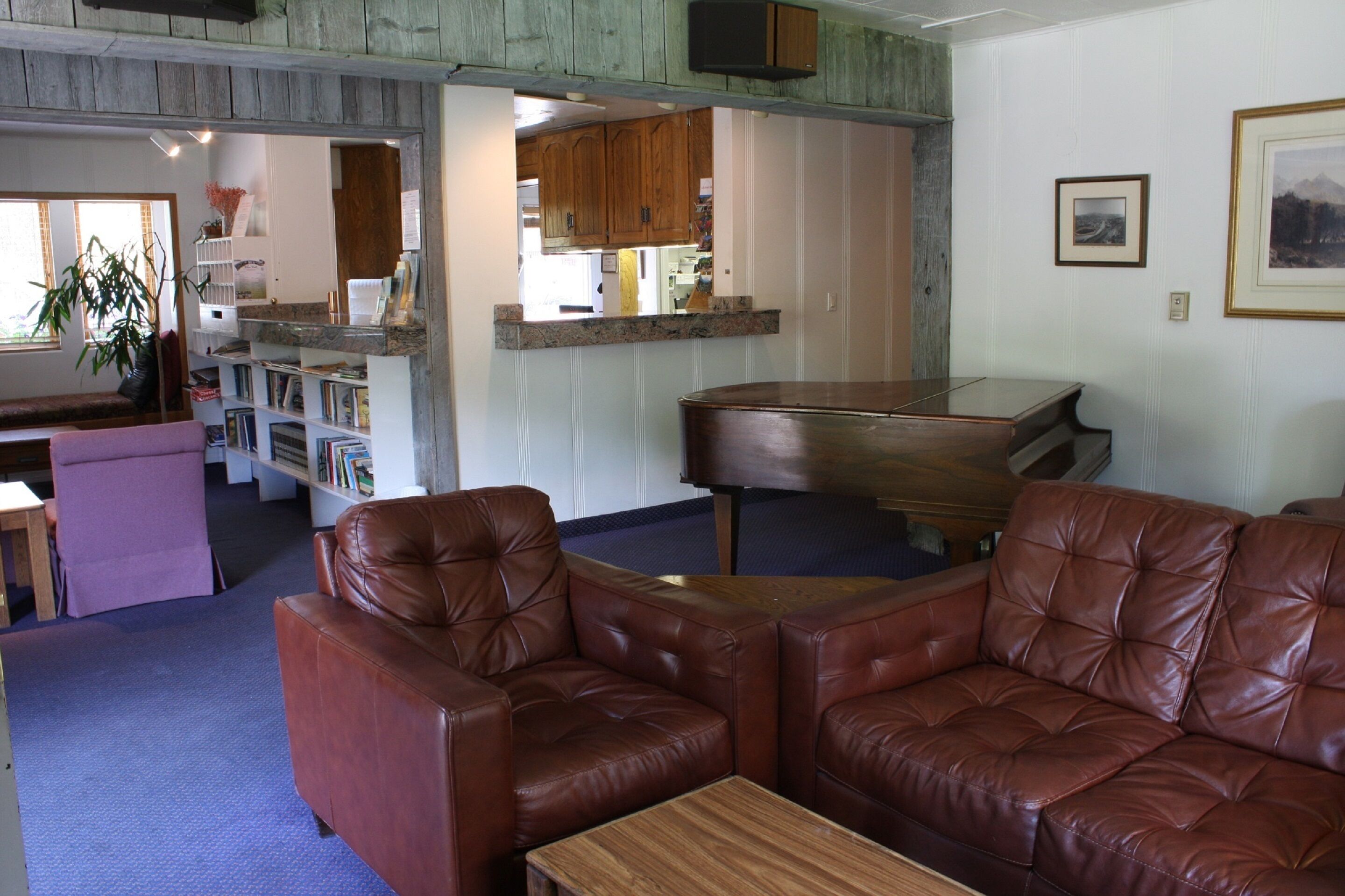 A living room with a brown leather sofa, a wooden coffee table, and a kitchen area in the background.