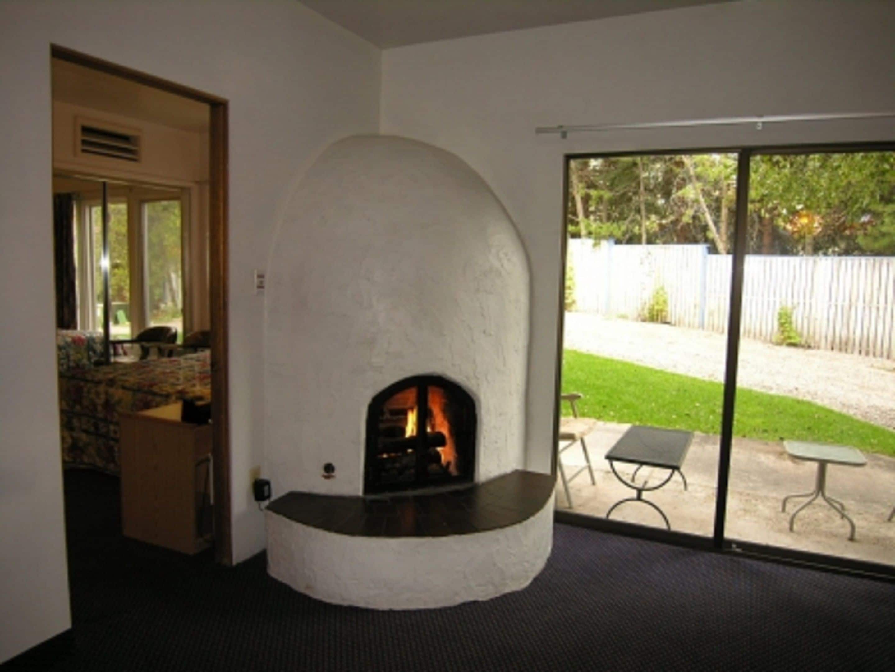 A room with a stone fireplace, a large sliding glass door leading to a patio, and a small table outside.