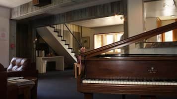 Un piano à queue se trouve dans une pièce spacieuse, et un escalier mène à un niveau supérieur.